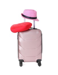 Photo of Red travel pillow and hat on suitcase against white background