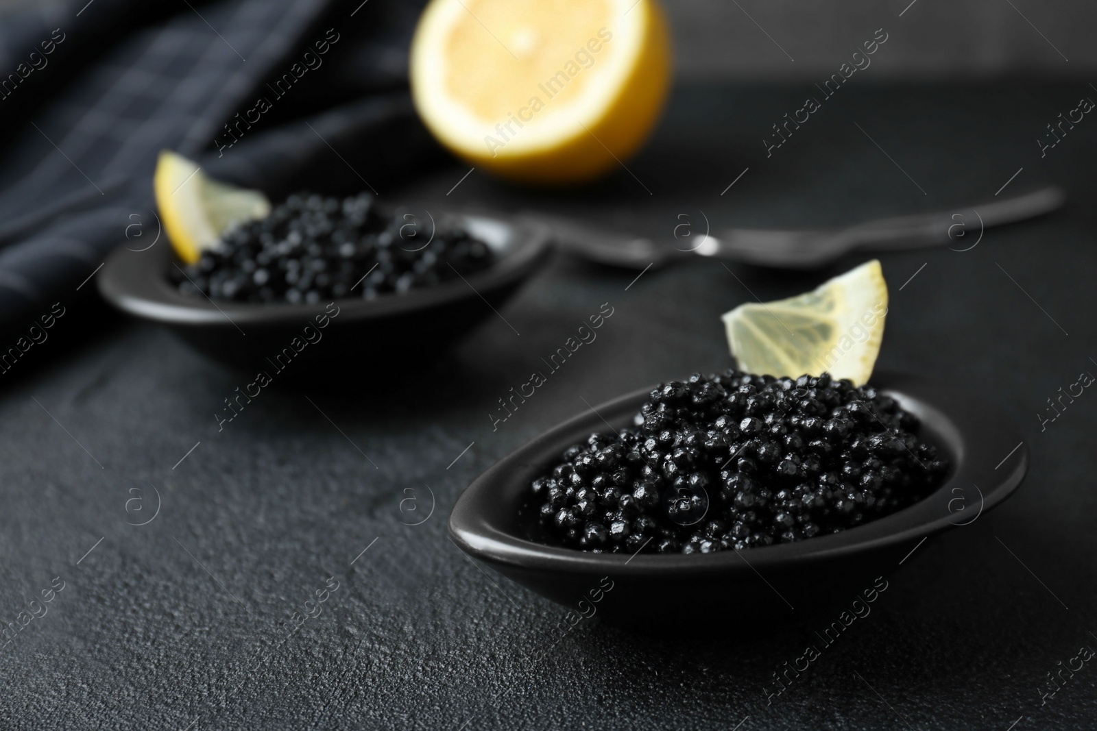 Photo of Bowls with black caviar on dark grey table