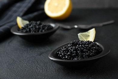 Photo of Bowls with black caviar on dark grey table