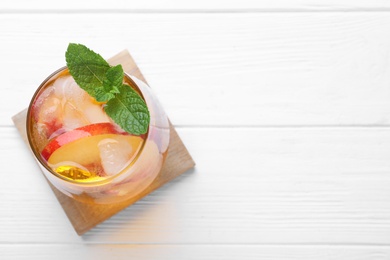 Photo of Delicious peach lemonade made with soda water on white wooden table, top view. Space for text