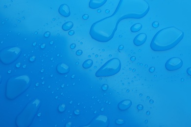 Drops of spilled water on blue background, top view