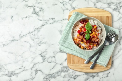 Photo of Delicious chili con carne served with rice on marble table, flat lay. Space for text