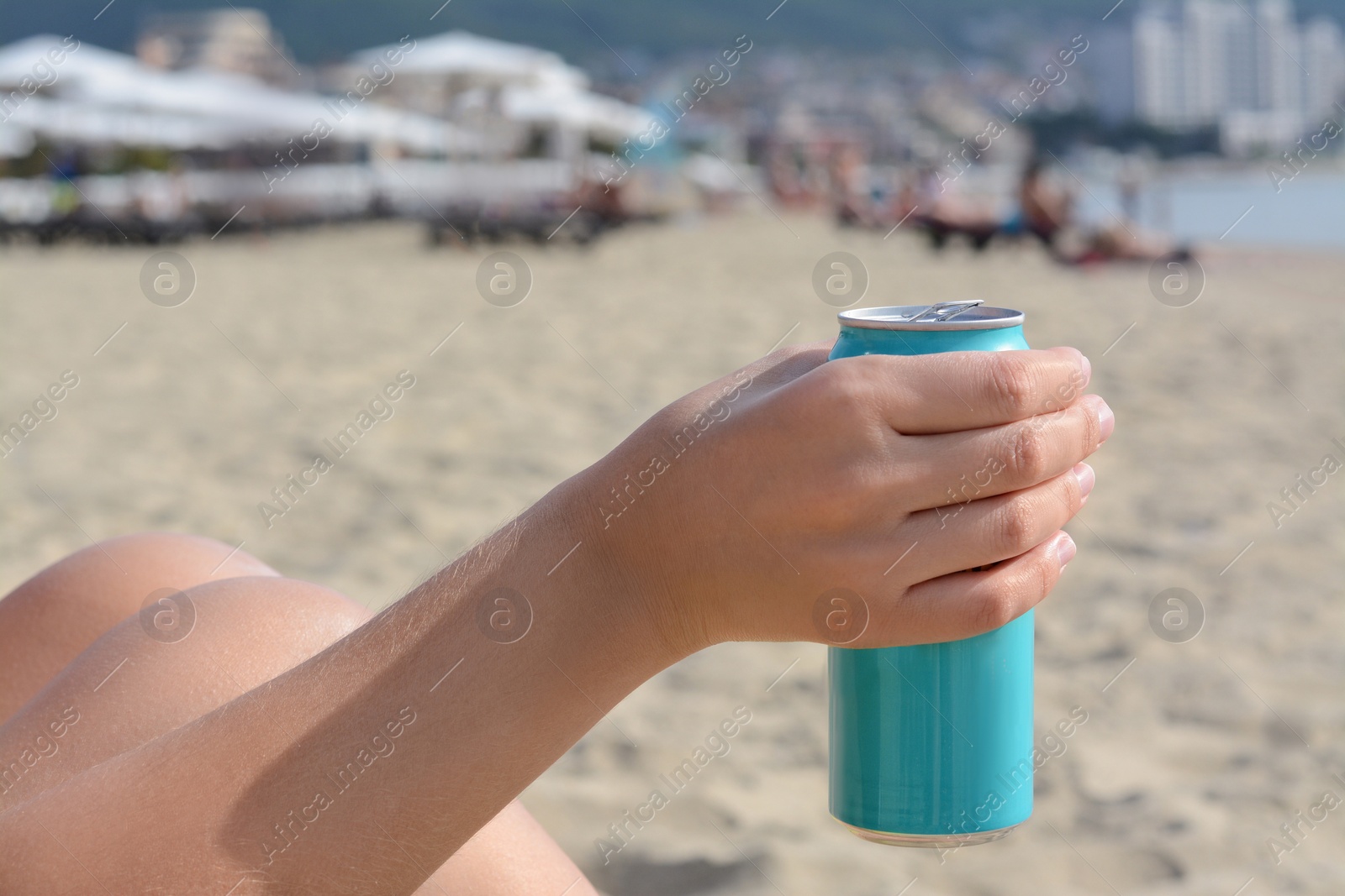 Photo of Woman holding aluminum can with beverage on beach, closeup