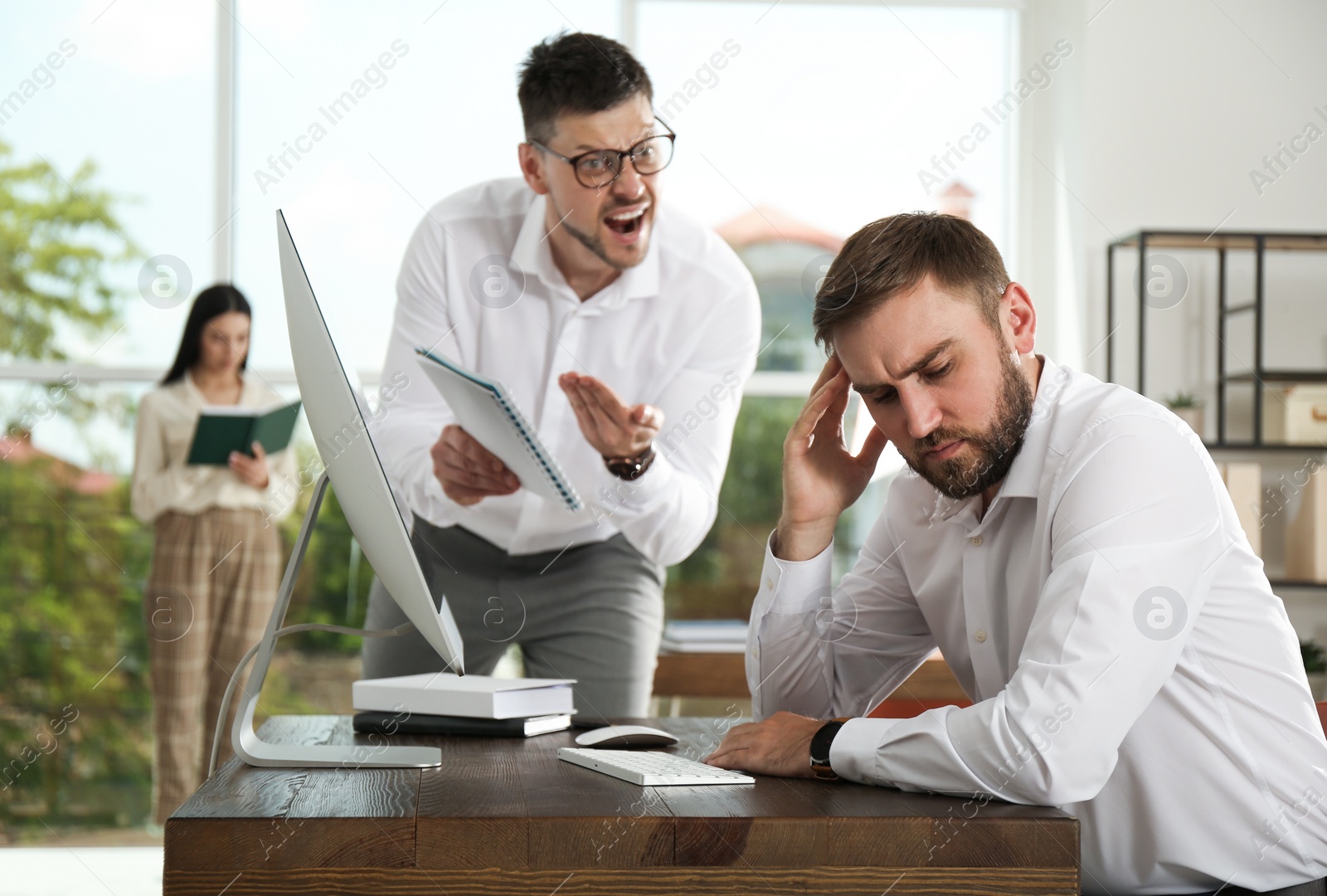 Photo of Boss screaming at employee in office. Toxic work environment