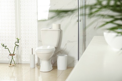 Photo of Toilet bowl near shower stall in modern bathroom interior