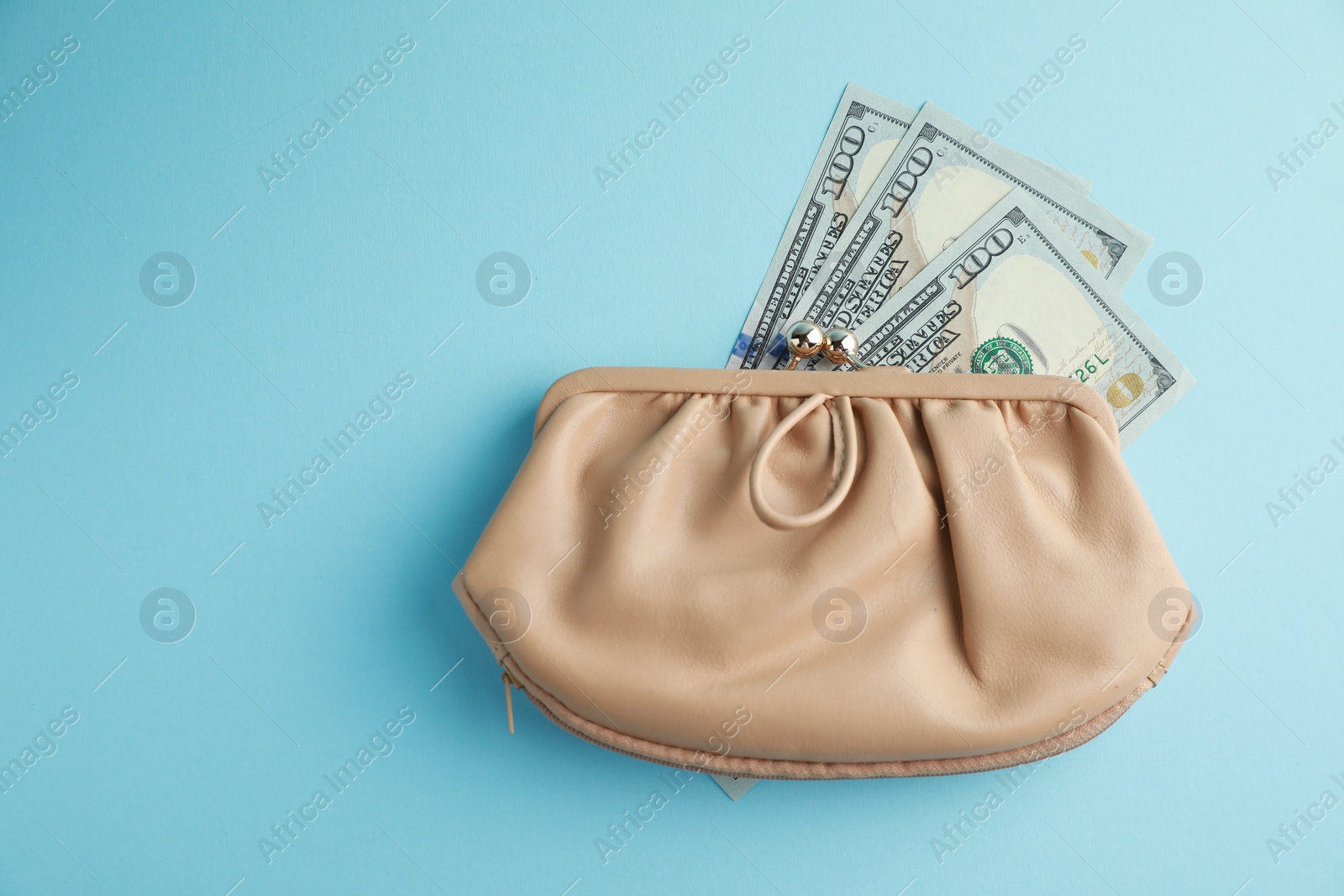 Photo of One stylish leather purse with money on light blue background, top view. Space for text