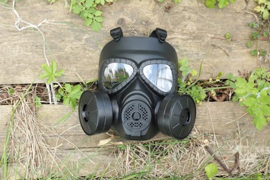 One gas mask on wooden surface outdoors, top view