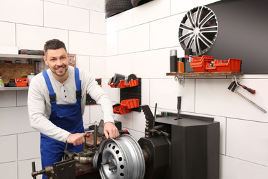 Photo of Mechanic working with car disk lathe machine at tire service