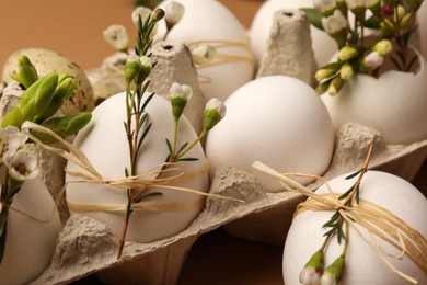 Festive composition with eggs and floral decor on brown background, closeup. Happy Easter