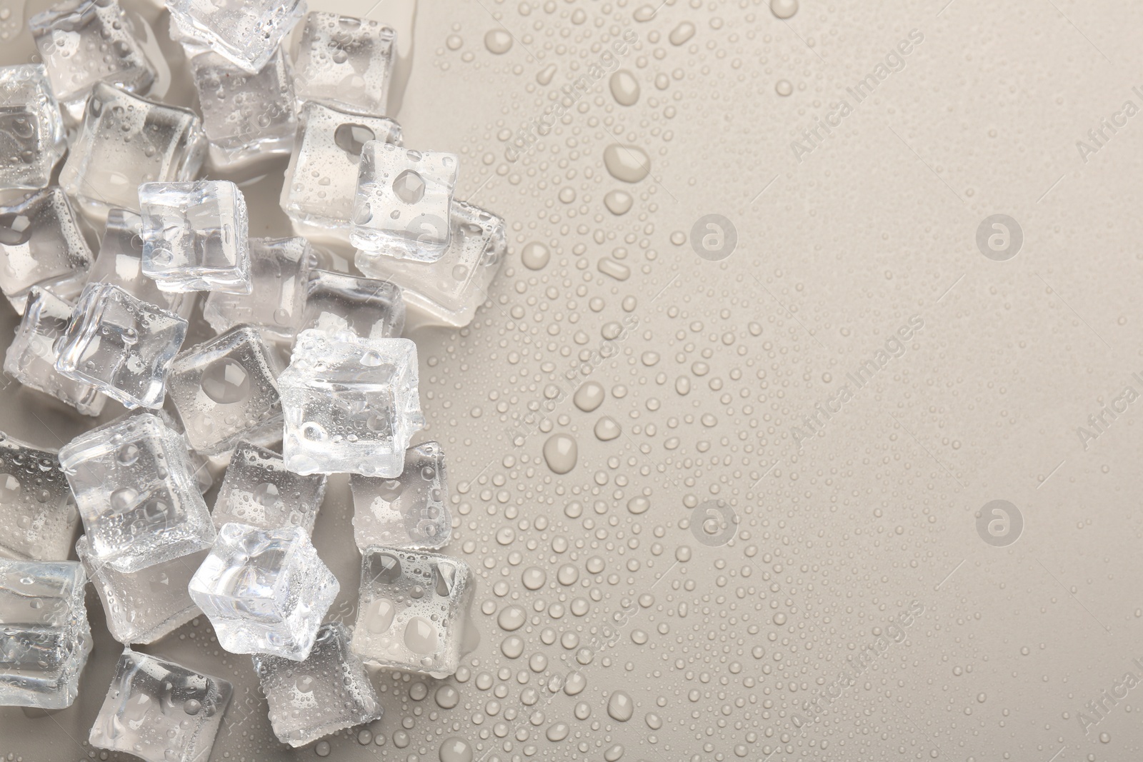 Photo of Melting ice cubes and water drops on light grey background, flat lay. Space for text