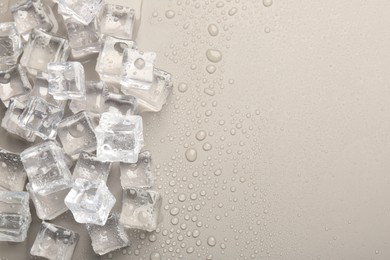 Melting ice cubes and water drops on light grey background, flat lay. Space for text