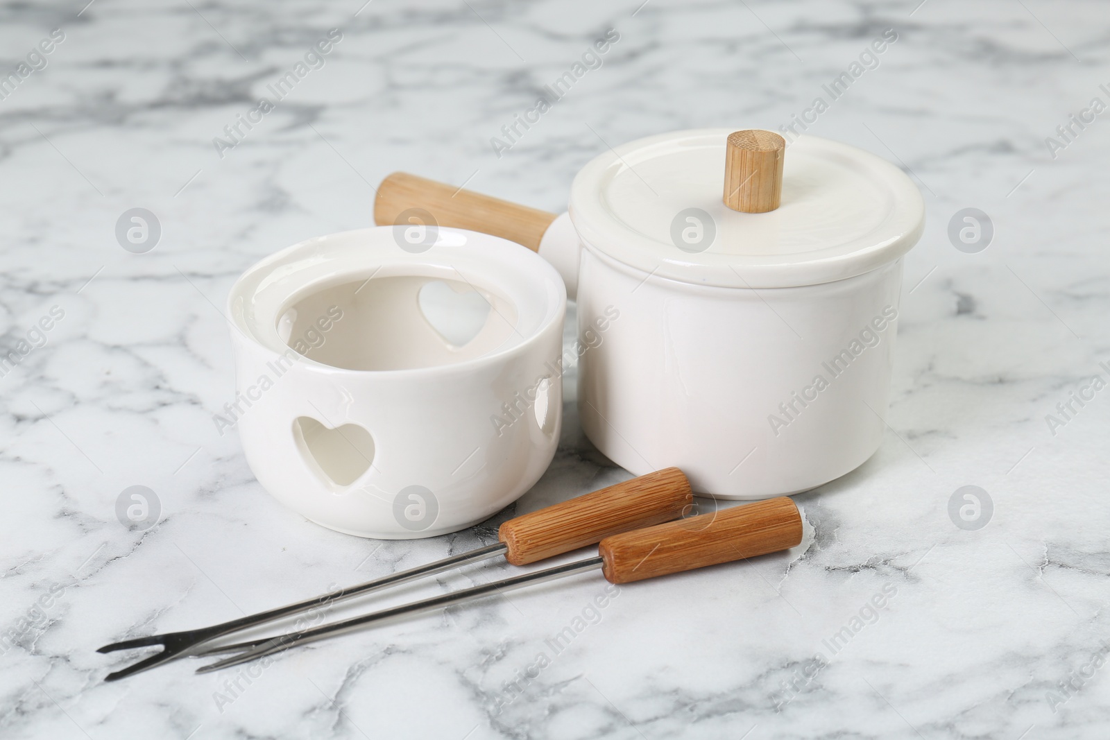 Photo of Fondue set on white marble table. Kitchen equipment