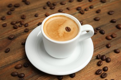 Cup of tasty coffee and beans on wooden table