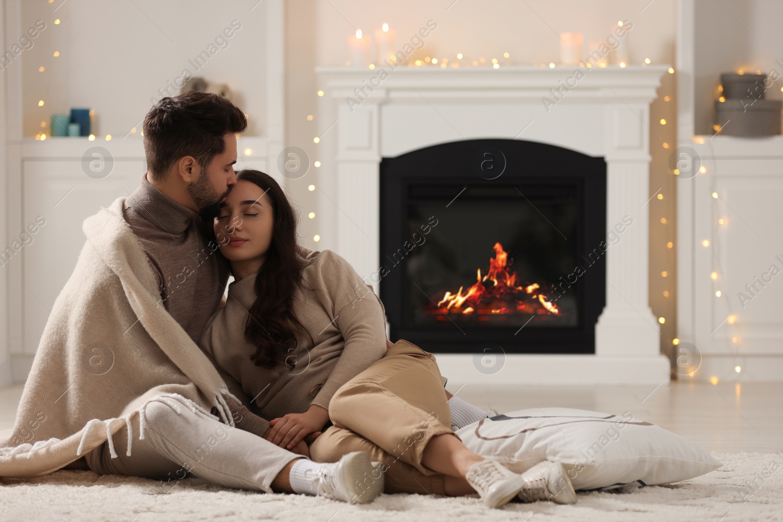 Photo of Young man kissing his girlfriend on soft carpet at home. Space for text