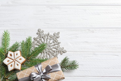 Flat lay composition with Christmas gift and fir branches on wooden background