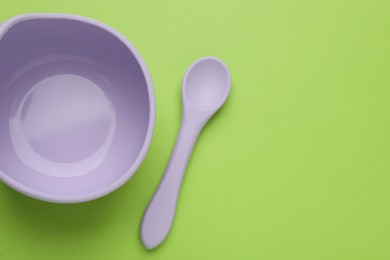 Plastic bowl and spoon on light green background, flat lay with space for text. Serving baby food