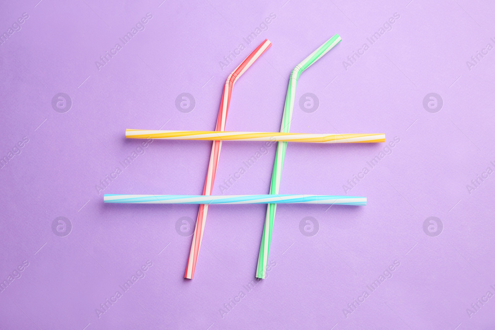 Photo of Hashtag symbol made of drinking straws on violet background, top view