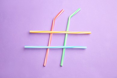 Photo of Hashtag symbol made of drinking straws on violet background, top view