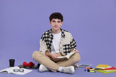 Photo of Portrait of student with notebook and stationery sitting on purple background