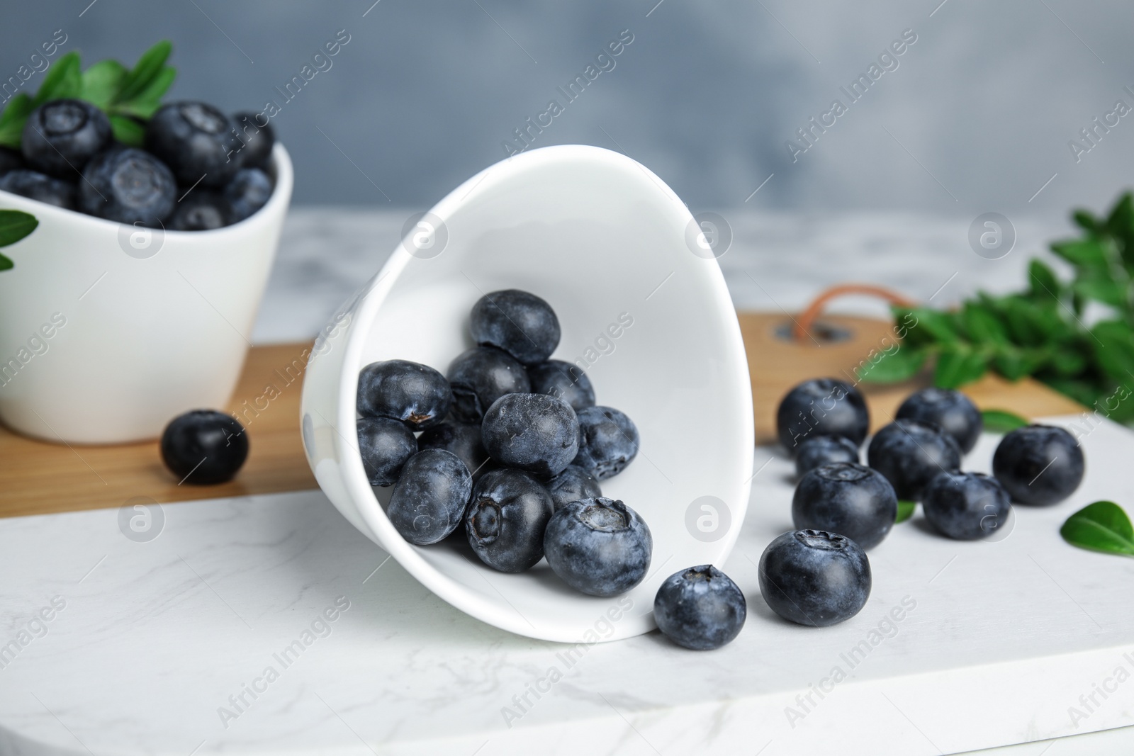 Photo of Board with bowl of tasty fresh blueberries on table