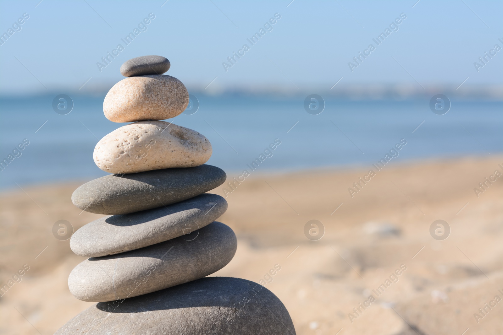 Photo of Stack of stones on sandy beach, closeup. Space for text