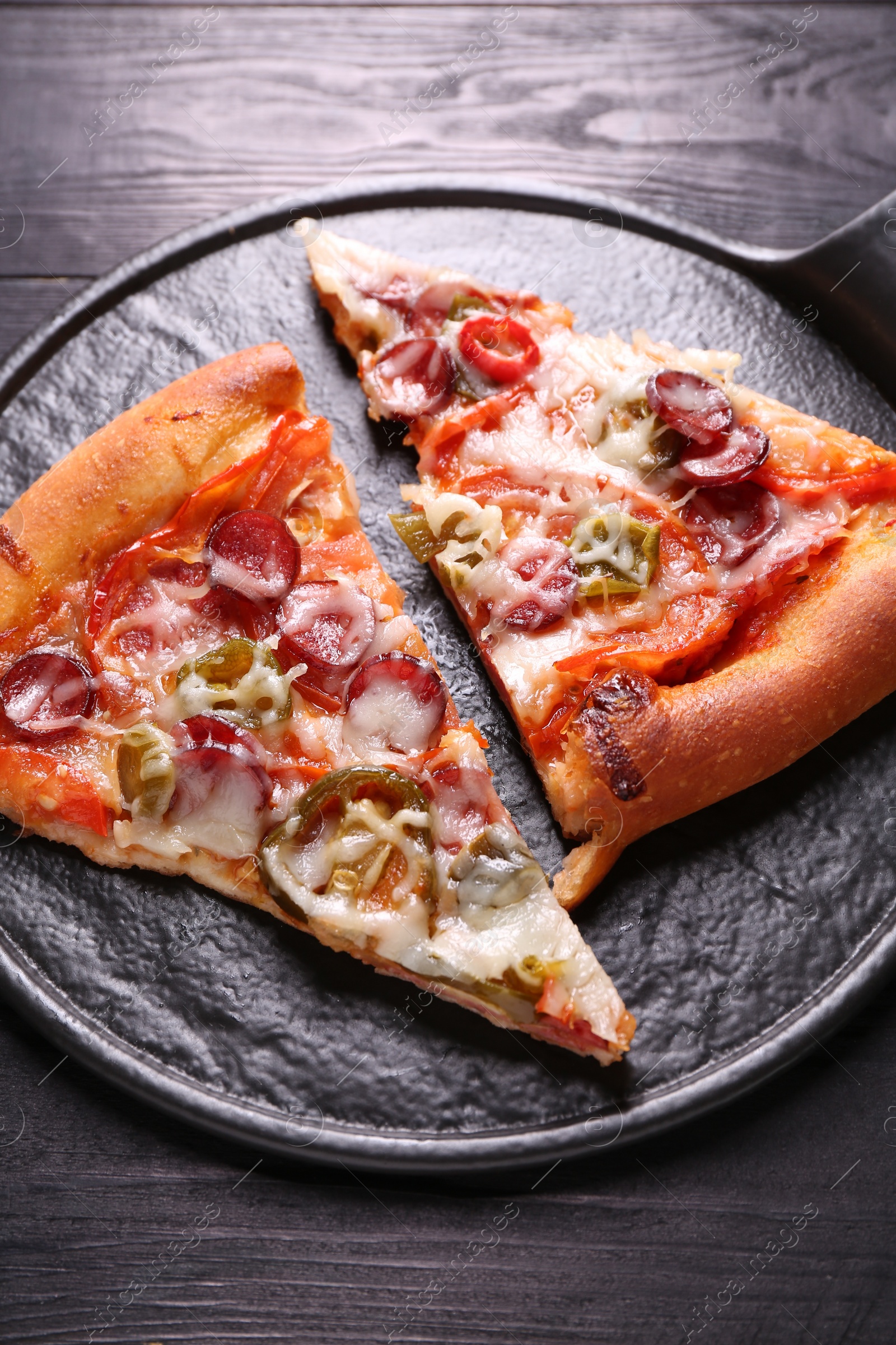 Photo of Board with pieces of delicious pizza Diablo on black wooden table, above view