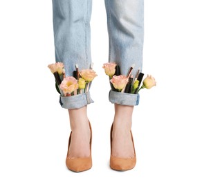 Photo of Woman in stylish jeans with roses and cosmetics on white background, closeup. Creative idea