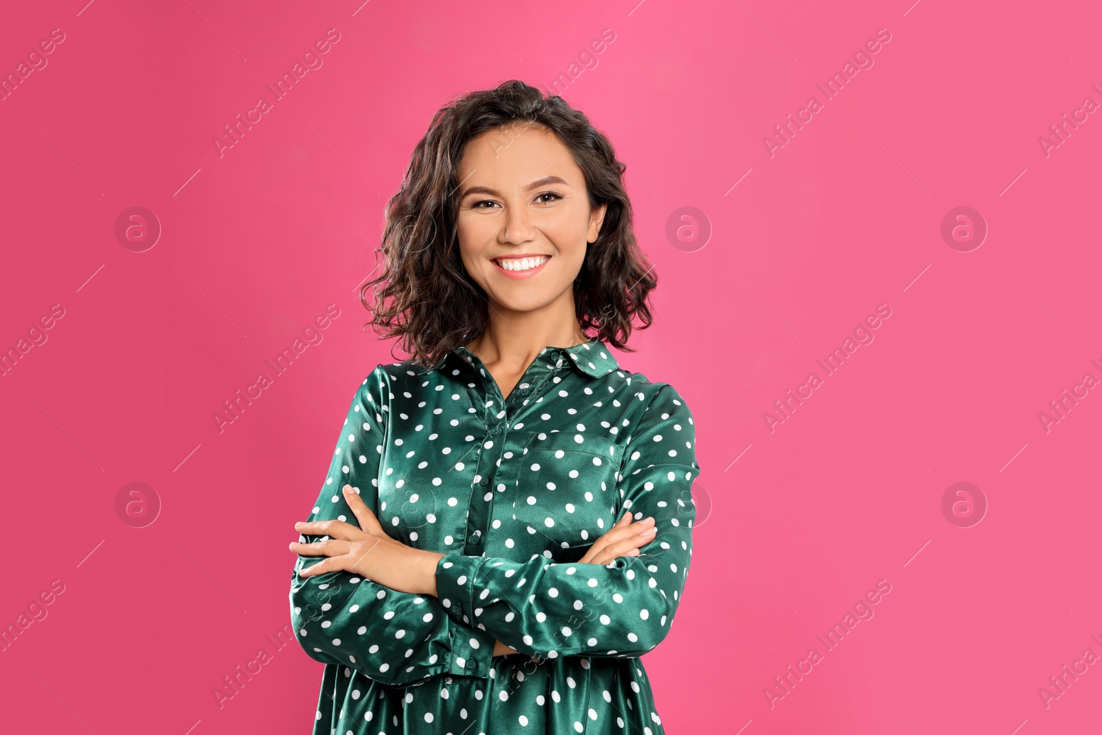 Photo of Happy young woman with crossed hands on pink background