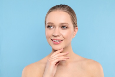 Portrait of young woman with beautiful face on blue background