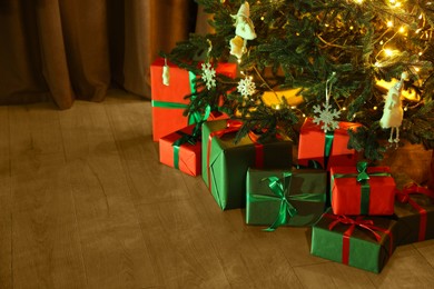 Photo of Beautifully wrapped gift boxes under Christmas tree indoors