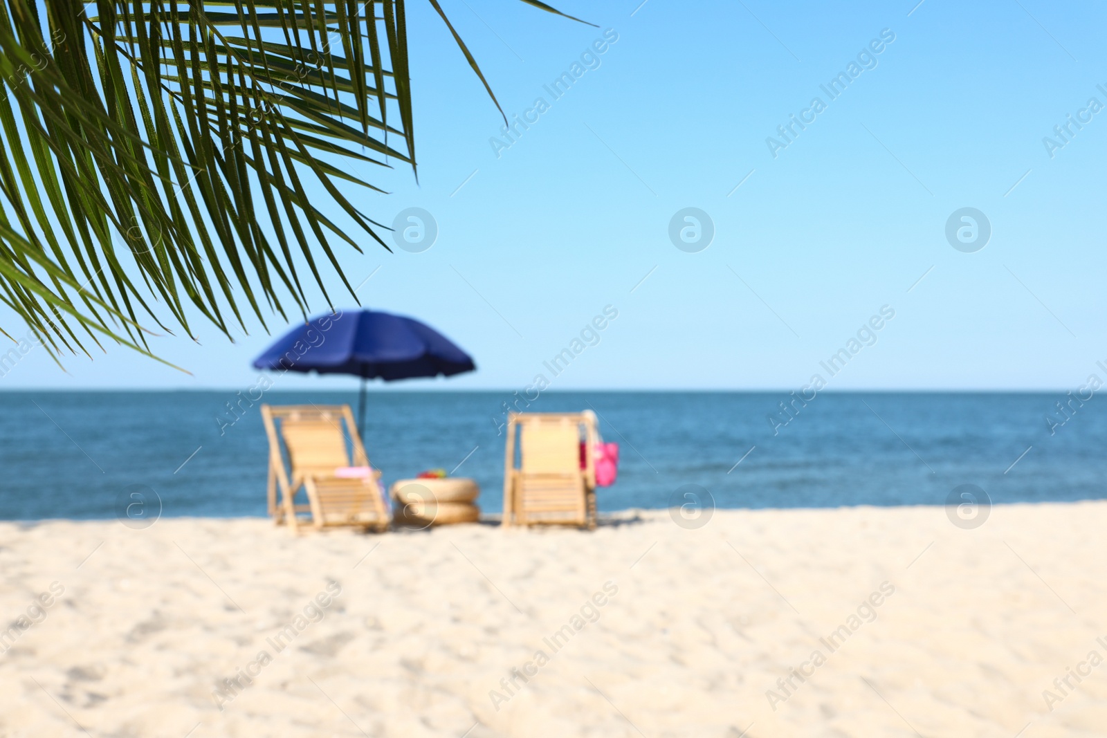 Photo of Wooden sunbeds and beach accessories on sandy shore