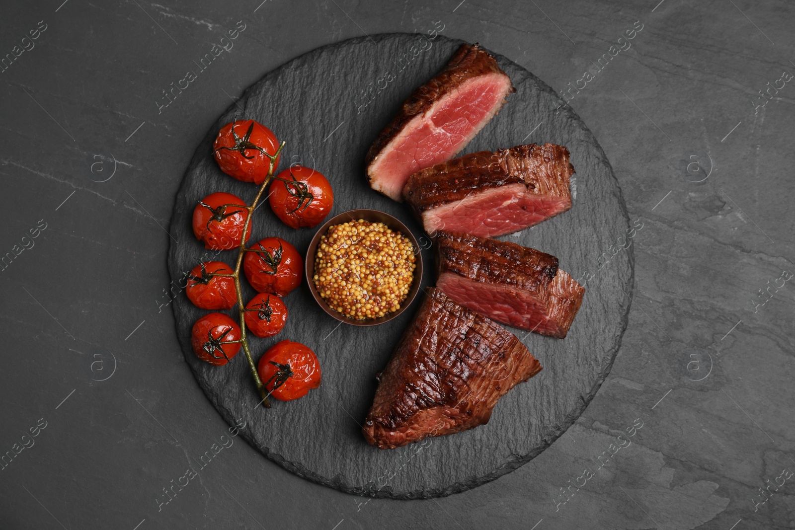 Photo of Delicious sliced beef tenderloin served on black table, top view