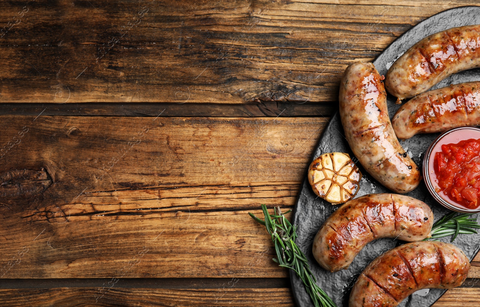 Photo of Tasty grilled sausages served on wooden table, flat lay. Space for text