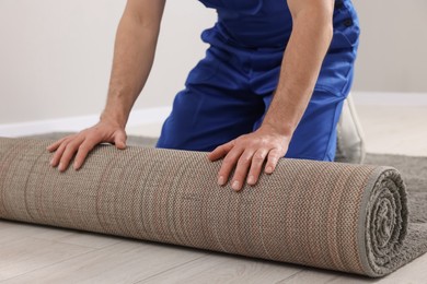Worker unrolling new carpet on floor in room, closeup