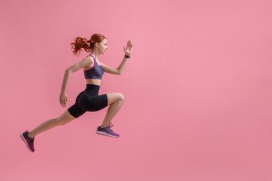 Young woman in sportswear jumping on pink background, space for text