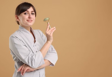 Cosmetologist with facial roller on beige background, space for text