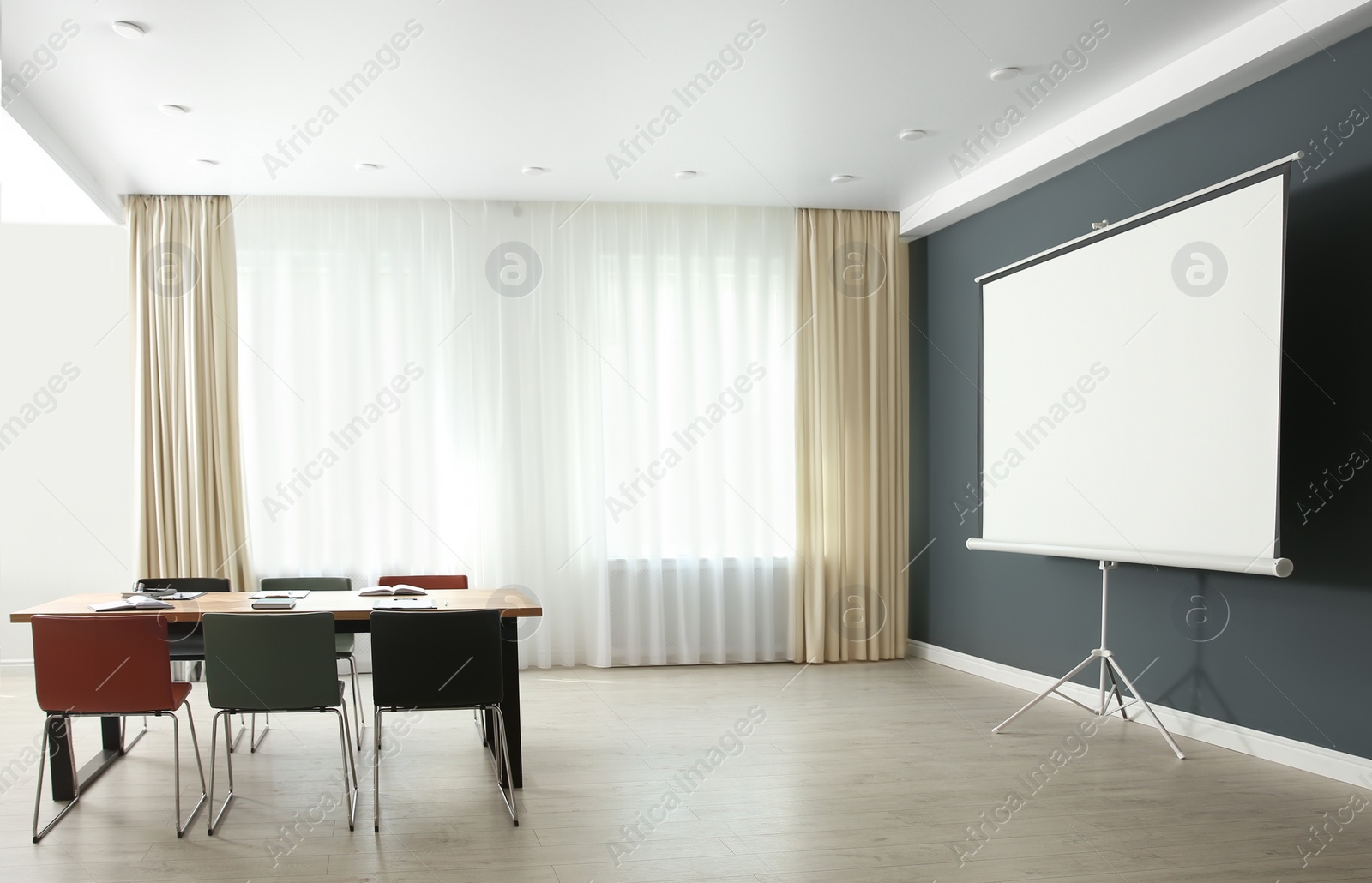 Photo of Modern meeting room interior with large table and projection screen