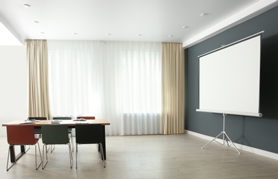 Photo of Modern meeting room interior with large table and projection screen