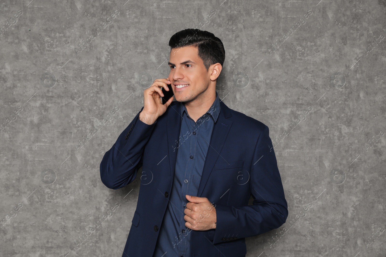 Photo of Portrait of businessman talking on phone against grey background