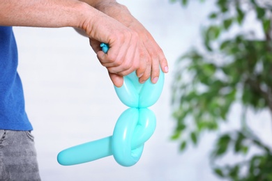 Photo of Man making balloon figure on blurred background, closeup. Space for text