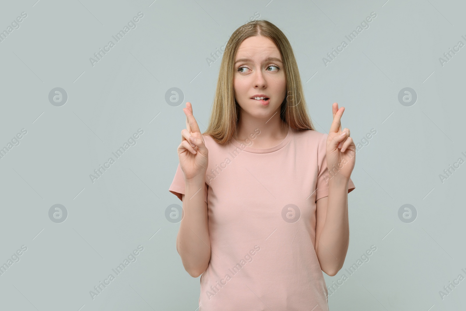 Photo of Woman crossing her fingers on grey background, space for text