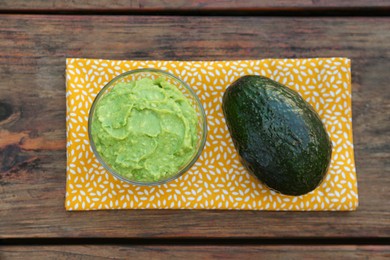Delicious guacamole made of avocados and whole fruit on wooden table, flat lay
