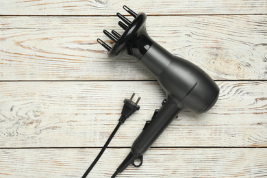 Photo of Hair dryer on white wooden table, top view. Professional hairdresser tool