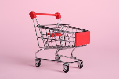 Photo of Small metal shopping cart on pink background