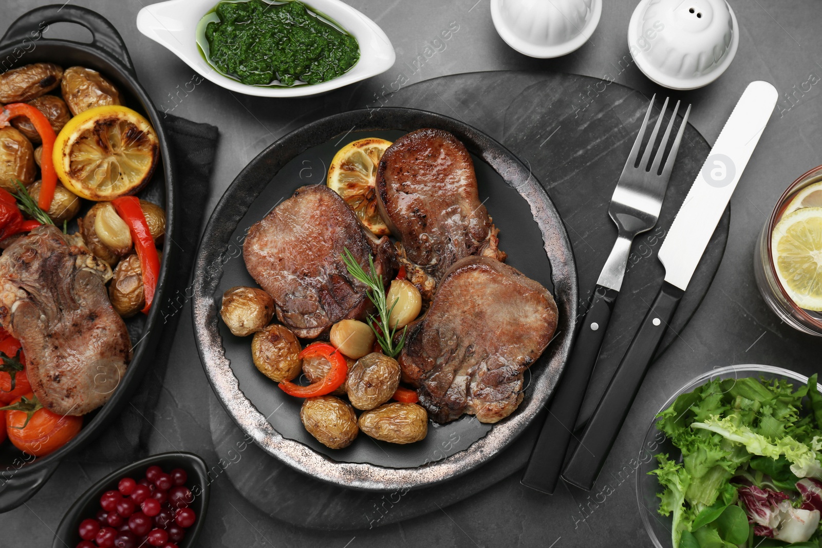Photo of Tasty beef tongue pieces with potatoes and ingredients on grey table, flat lay