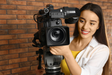 Photo of Operator with professional video camera near brick wall