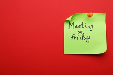 Photo of Paper note with words Meeting on Friday pinned to red background, space for text