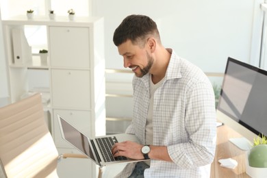 Photo of Freelancer working on laptop near table indoors