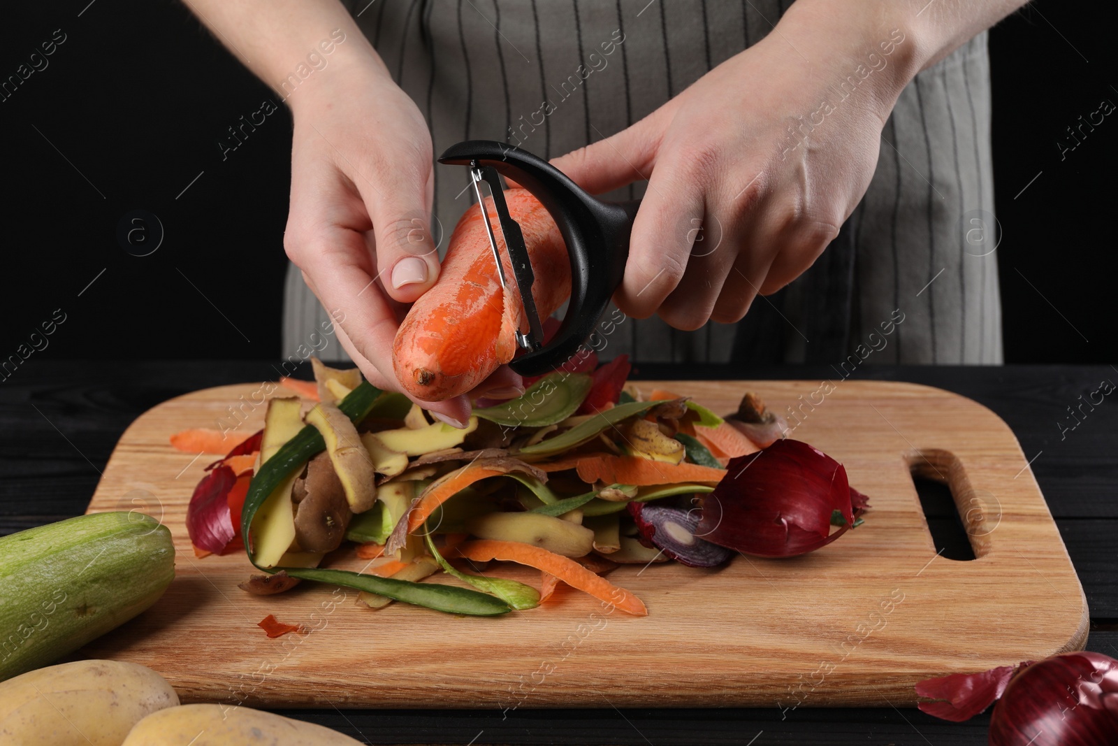 Photo of Woman peeling fresh carrot at table, closeup