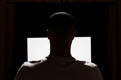 Photo of Man using computer at night, back view. Internet addiction